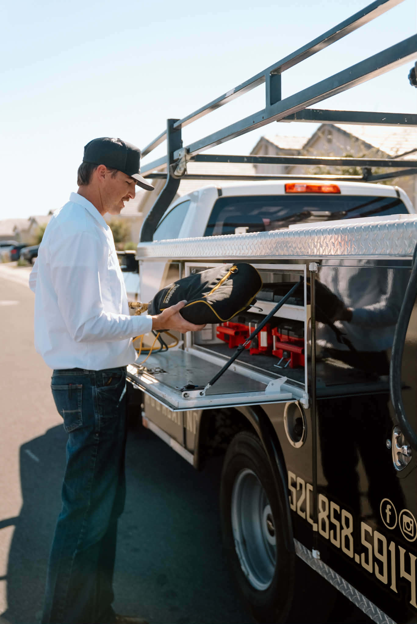 Outlaw Air technician lifting a tool bag out of a side compartment on the service truck