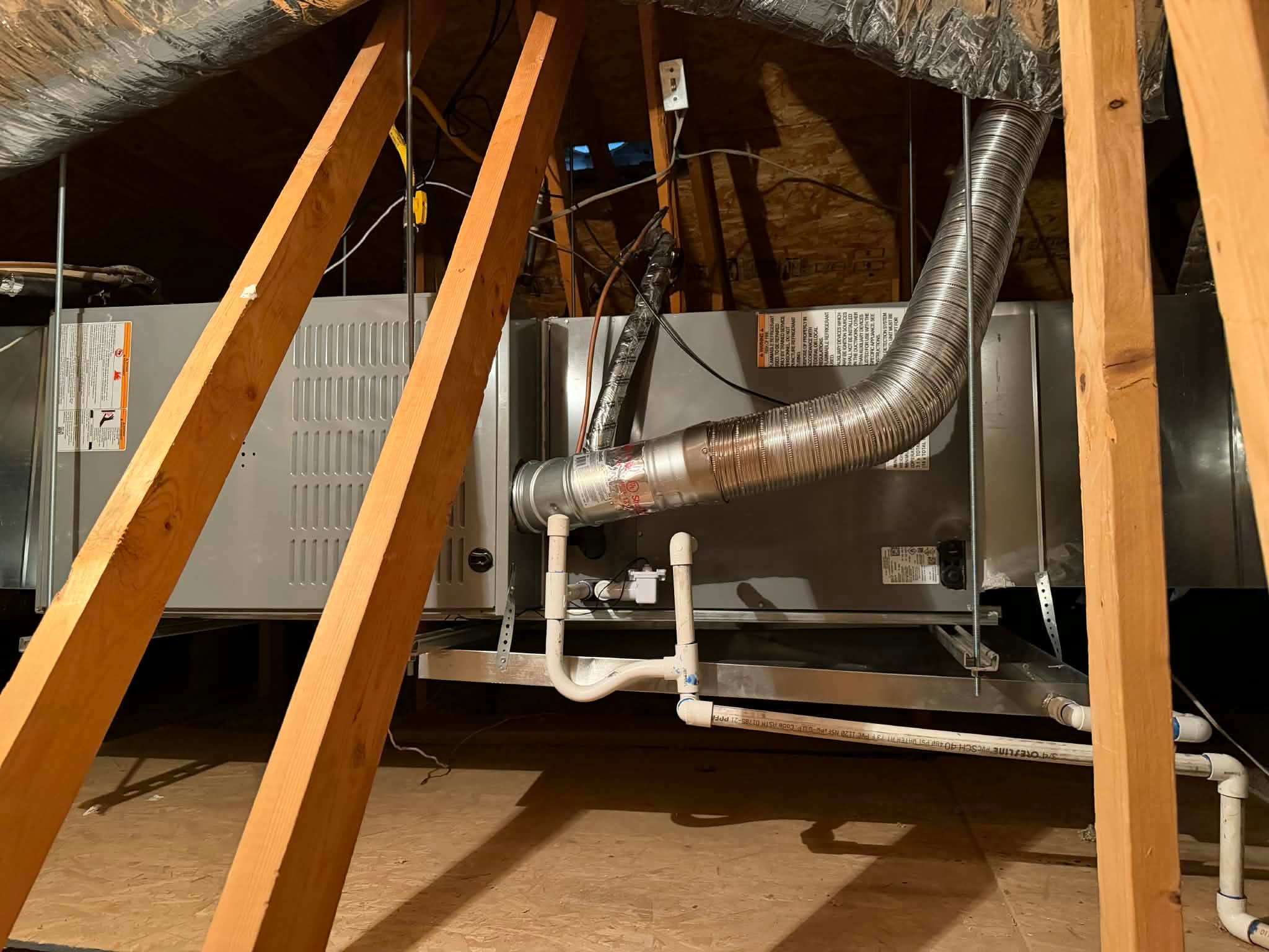 Furnace in a home attic after an Outlaw Air replacement, with tidy PVC drain lines