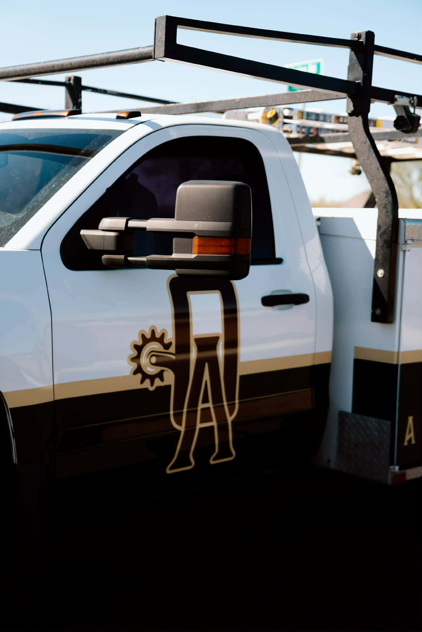 Door of the Outlaw Air service truck with the OA spur logo and a ladder rack overhead
